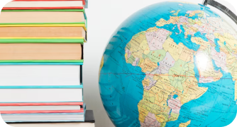 Globo terrestre azul ao lado de uma pilha alta de livros coloridos